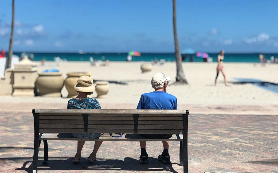 Couple de retraités assis sur un banc face à la plage, symbolisant une retraite sereine grâce à un bilan retraite réalisé avec un expert-comptable.